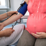 NP taking blood pressure reading of pregnancy patient with autoimmune disease