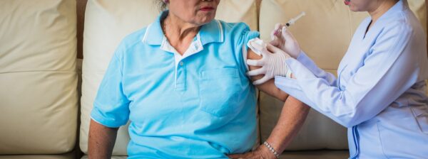 older woman getting vaccine from NP